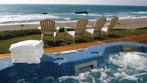 A poolside area with a view of the ocean, several Adirondack chairs, and a stack of white towels.