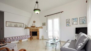 Un saló amb un sofà, una taula de centre de vidre, una llar de foc, una televisió i obres d'art a les parets.