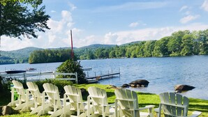 A lakeside view with white Adirondack chairs and a dock. - Charming lake front cabin on Highland Lake (Andover)