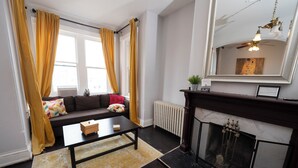 A living room with a sofa, a fireplace, and a large mirror. - Cap Hill 1-level Loft-style 2 Bedroom, near Capitol, Eastern MarketFREE Parking, (Washington)