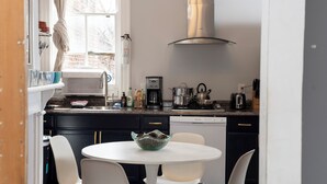 A compact kitchen with a round dining table, white chairs, and a coffee machine. - Cap Hill 1-level Loft-style 2 Bedroom, near Capitol, Eastern MarketFREE Parking, (Washington)