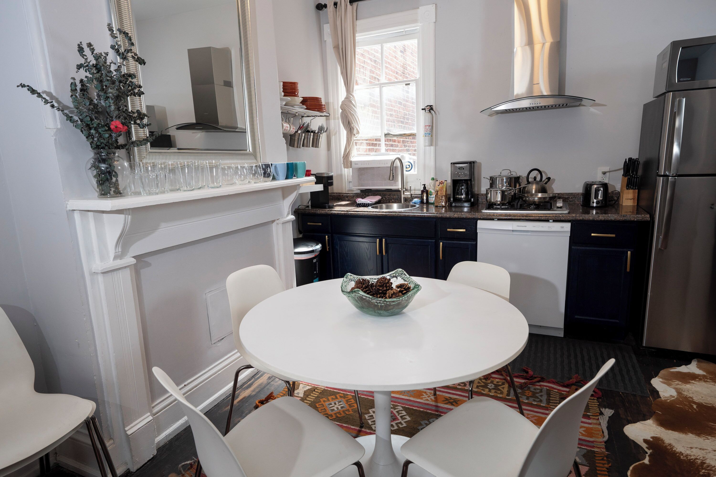 A modern kitchen with a white dining table, dark cabinets, and a stainless steel refrigerator.