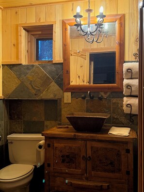 A rustic bathroom with a wooden vanity, a large basin sink, a toilet, and a chandelier. - Colorado Dream Vacation!5 min to Lake House!Next to nothing,close to everything! (Evergreen)