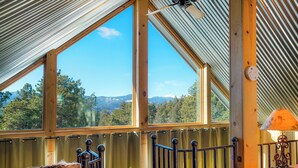 Ein Zimmer mit großen Fenstern und Blick auf einen Wald und Berge.