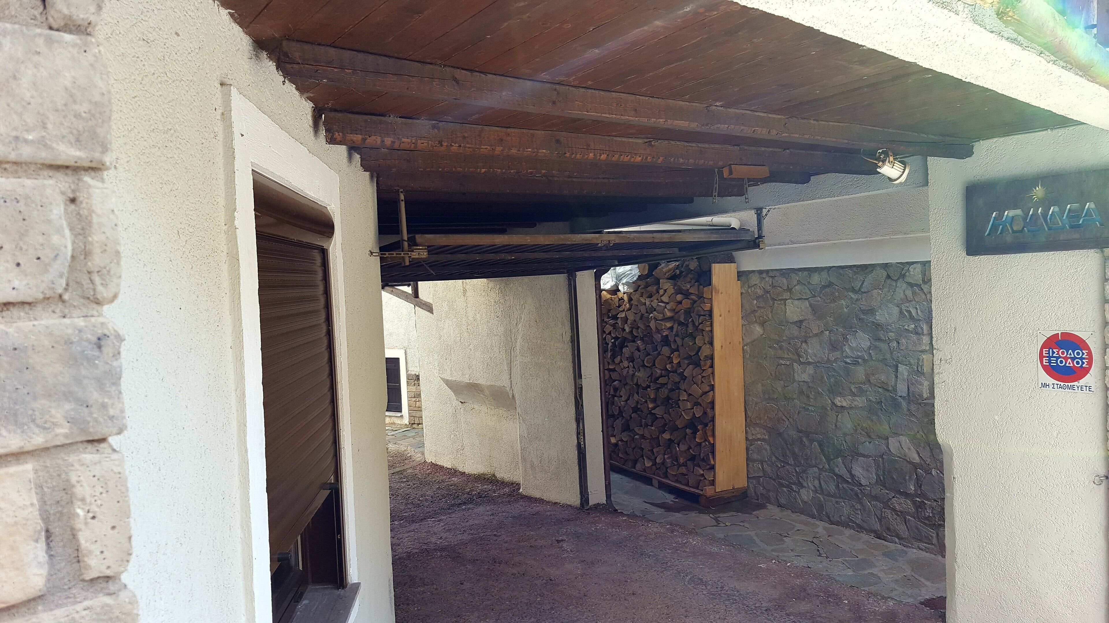 A covered outdoor area with a stone wall and a pile of firewood.
