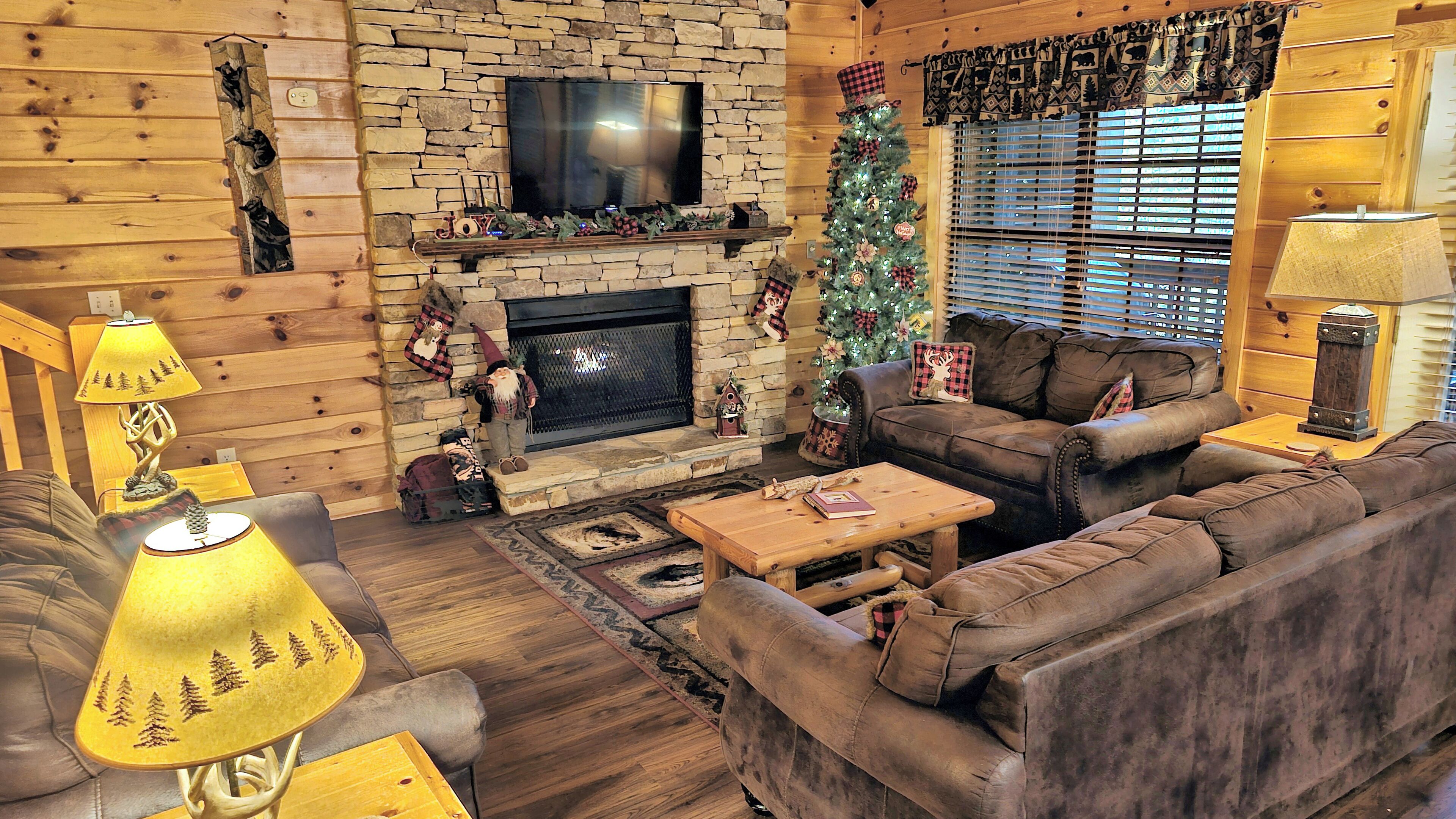 L’intérieur d’un chalet confortable, avec une cheminée en pierre, des murs en bois, un canapé en cuir et un sapin de Noël.
