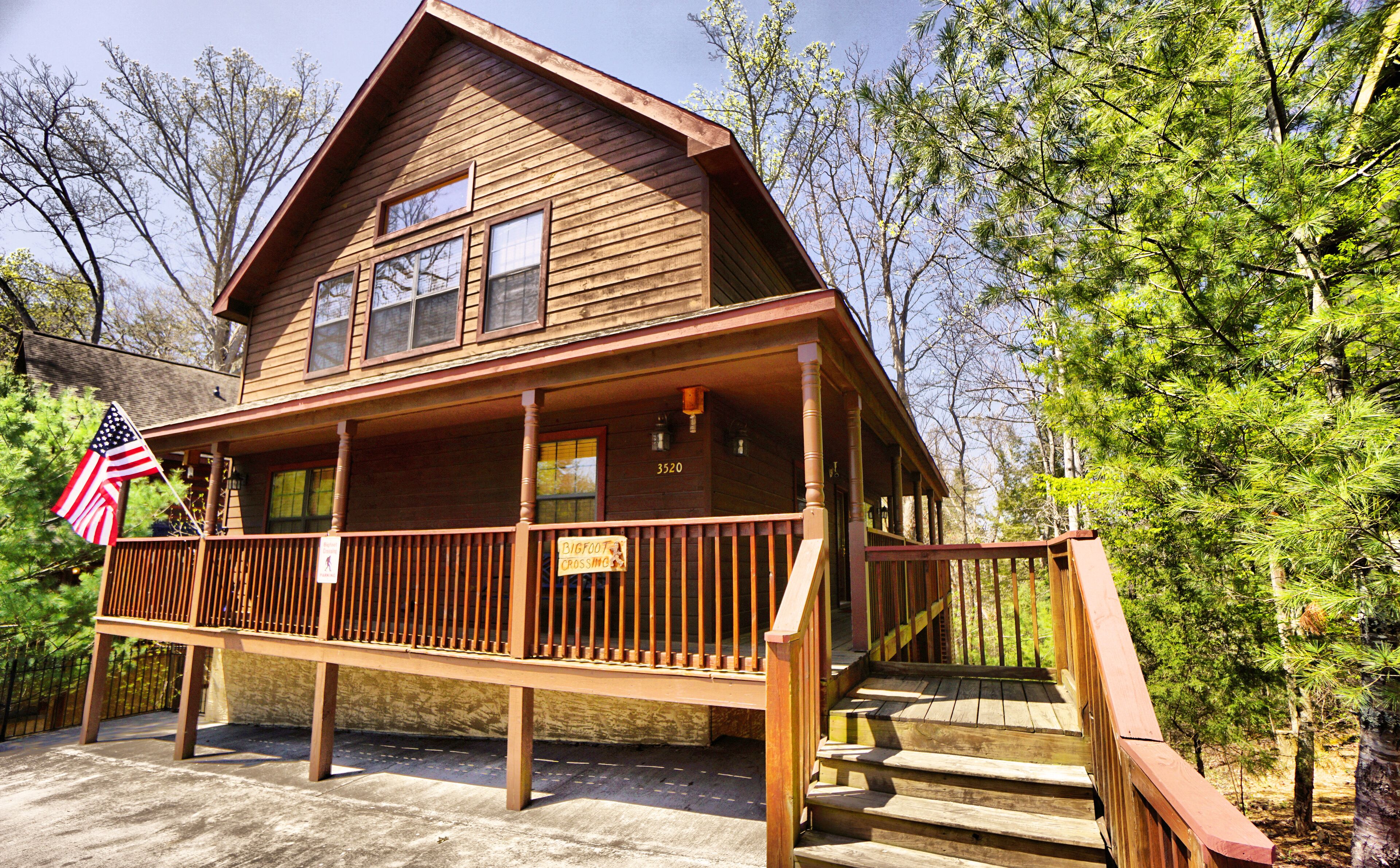 A wooden cabin with a porch, a staircase, and an American flag.