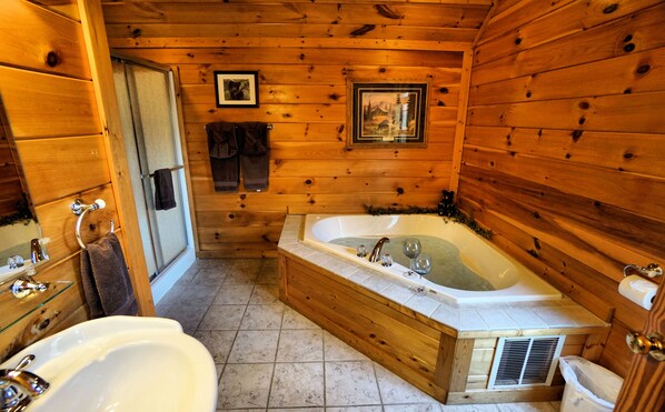 A wooden cabin bathroom with two sinks, a bathtub, and a shower.