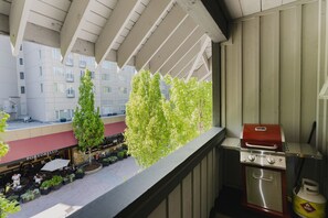 Ein Balkon mit Grill und Blick auf ein Restaurant darunter.