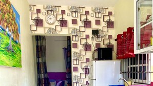 A compact kitchen with a refrigerator, stove, and sink. There is a dining area with a table and chairs. The kitchen has a decorative wall with square patterns and a clock. - Maria Bonita, Locate Near The Center Of The Higuey City (Higüey)