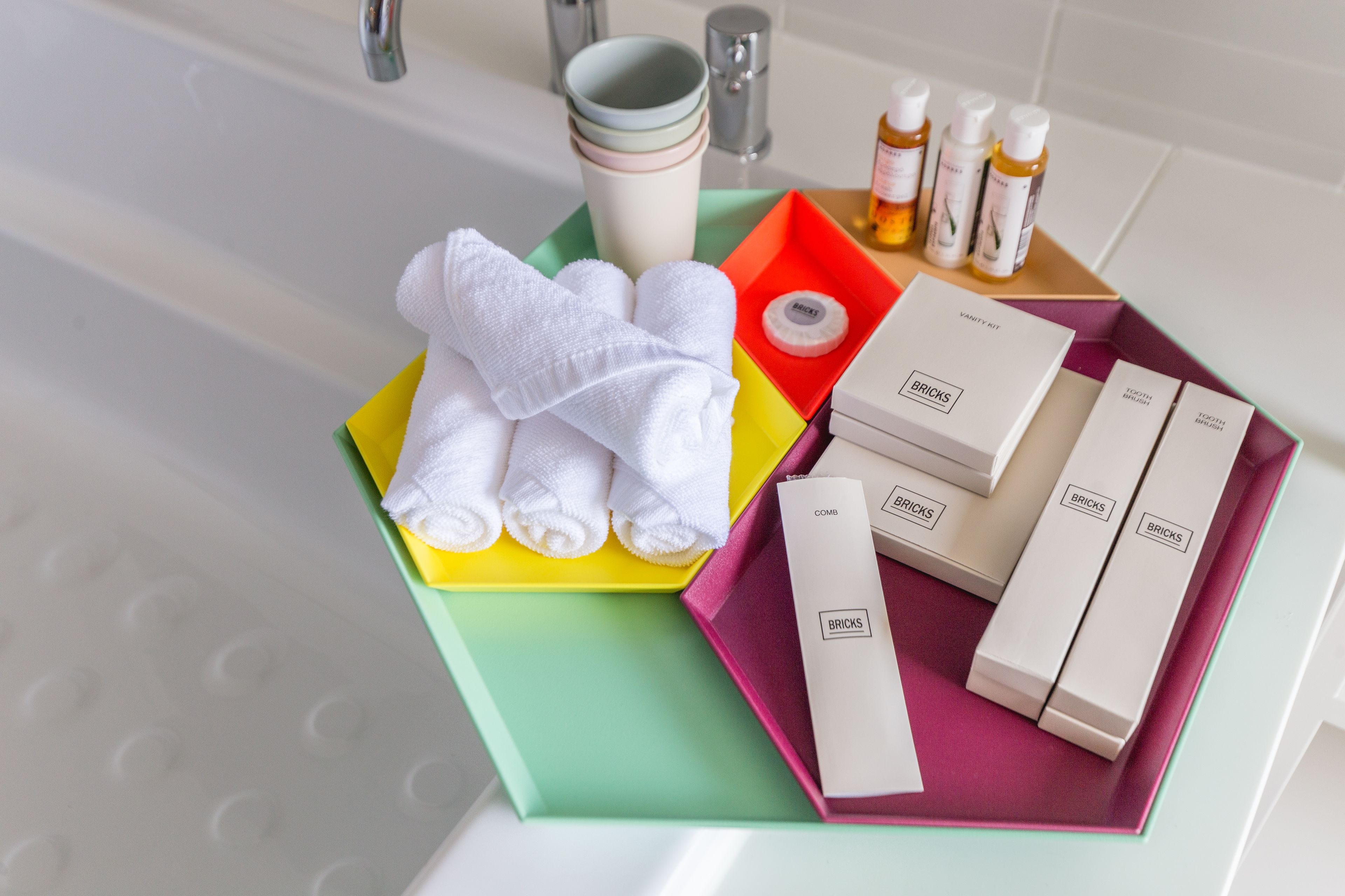 A bathroom with a bathtub, a set of toiletries including a comb, and a box of Bricks body wash.
