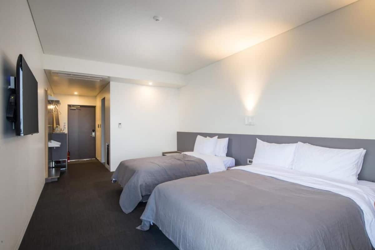 A hotel room with two beds, a TV, a desk, and a bathroom.