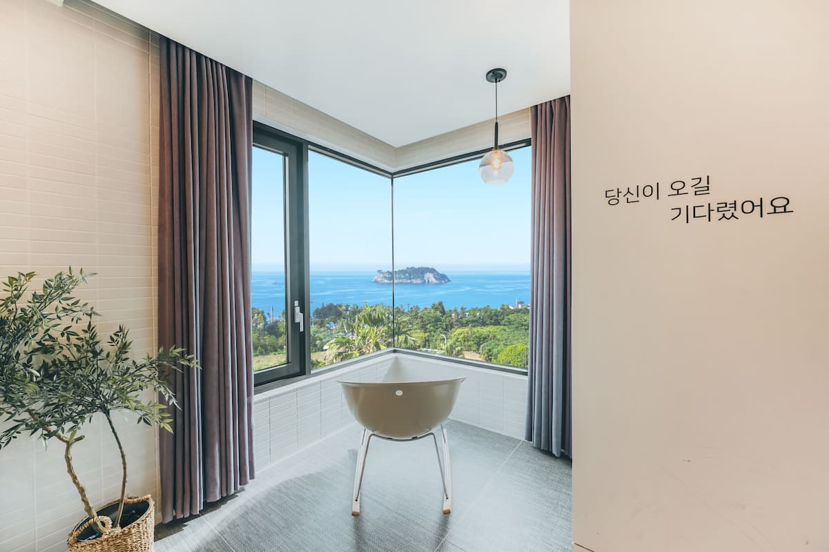 A modern room with a large window, a view of the sea, and a small table.
