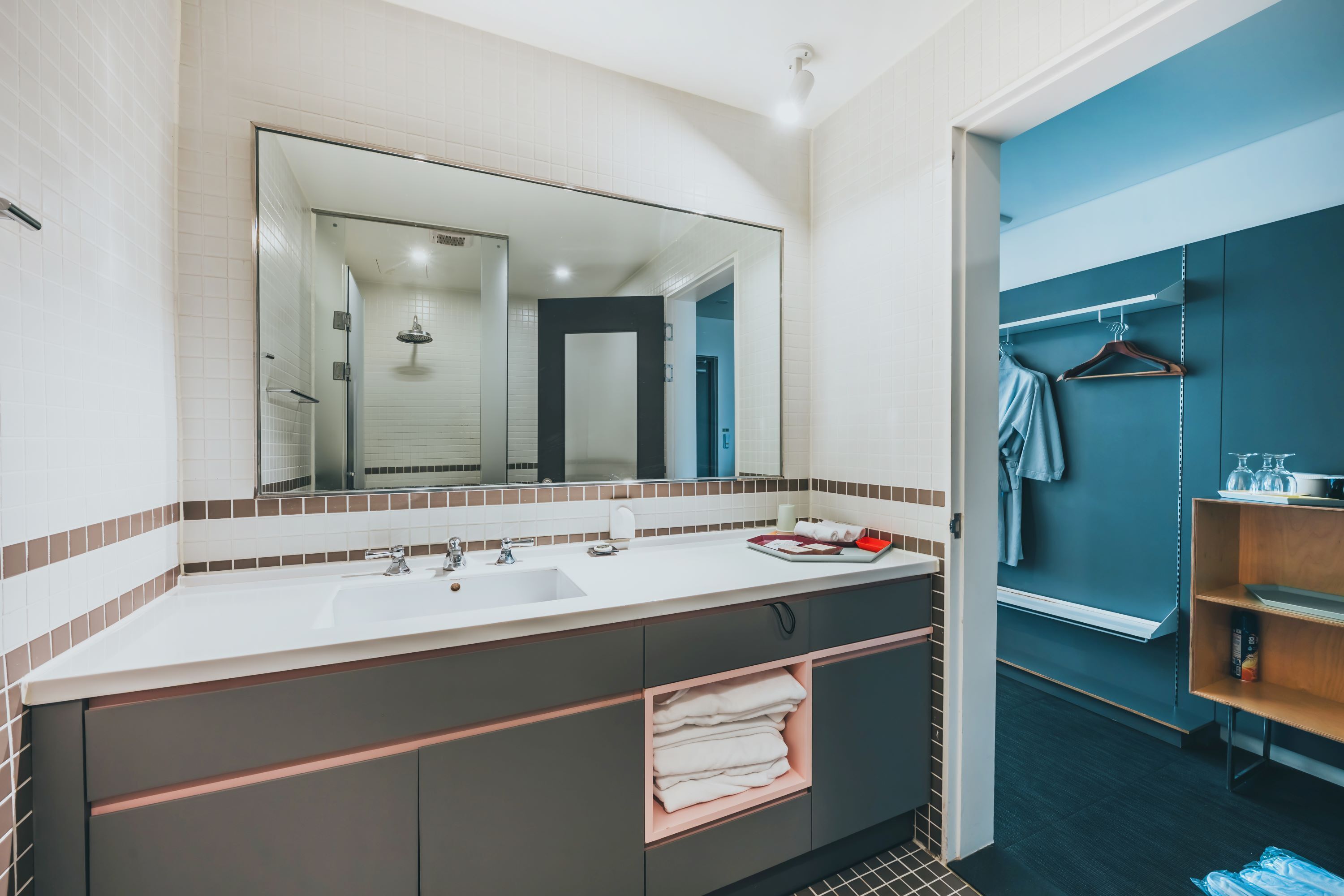 Un baño moderno con un espejo grande, lavamanos dobles y un perchero para toallas.