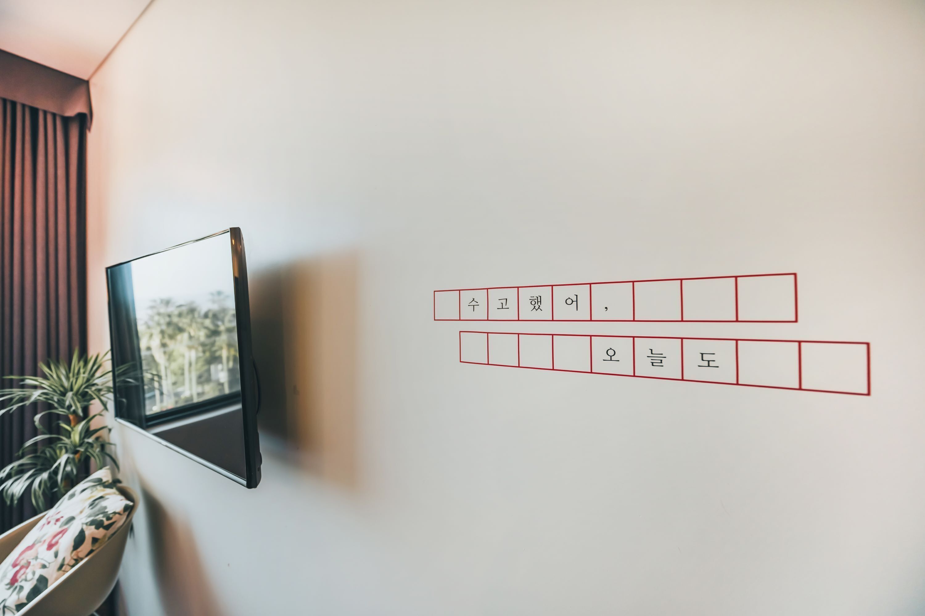 Seinälle asennettu televisio ja koristeellinen seinä, jossa on koreankielisiä kirjoitusmerkkejä.