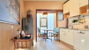 A modern kitchen with wooden paneling, a dining area with wicker chairs, and a large flat-screen TV mounted on the wall.