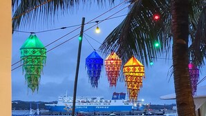 A beach with a wooden bench, a palm tree, and a view of a ship named 'Perries' docked at a pier. - S-E Hotel and Residence (Malay)