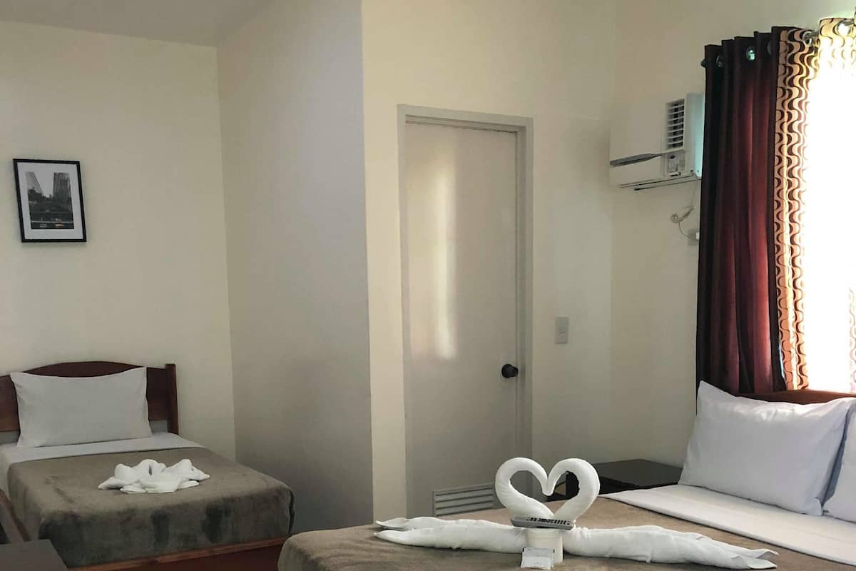 Habitación de hotel con dos camas, un escritorio y una puerta.