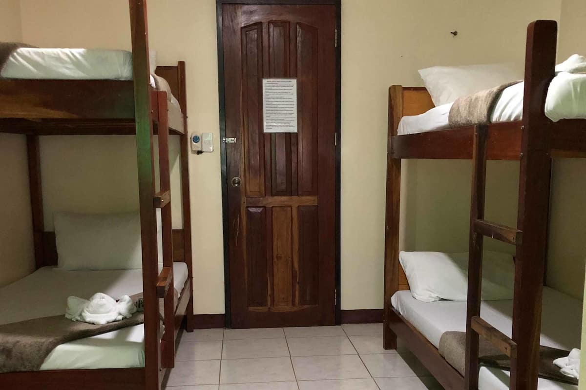 Una habitación con literas, una puerta de madera y piso de baldosas.