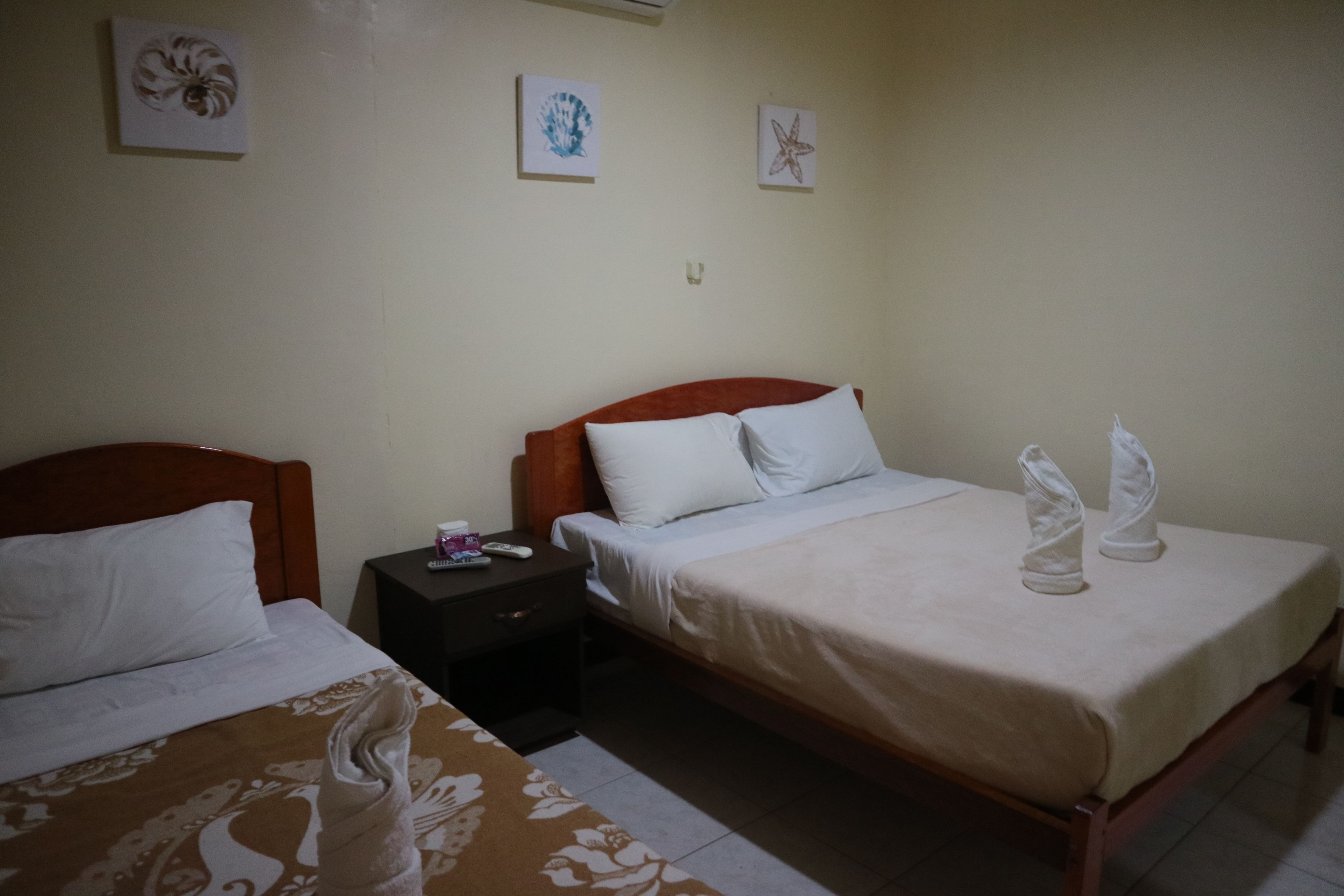 A hotel room with two beds, a nightstand, and wall art.
