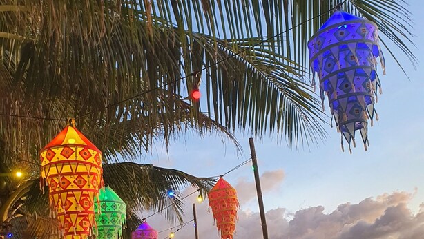 A beach setting with colorful hanging lanterns, a tented area, and beach chairs. - S-E Hotel and Residence (Malay)