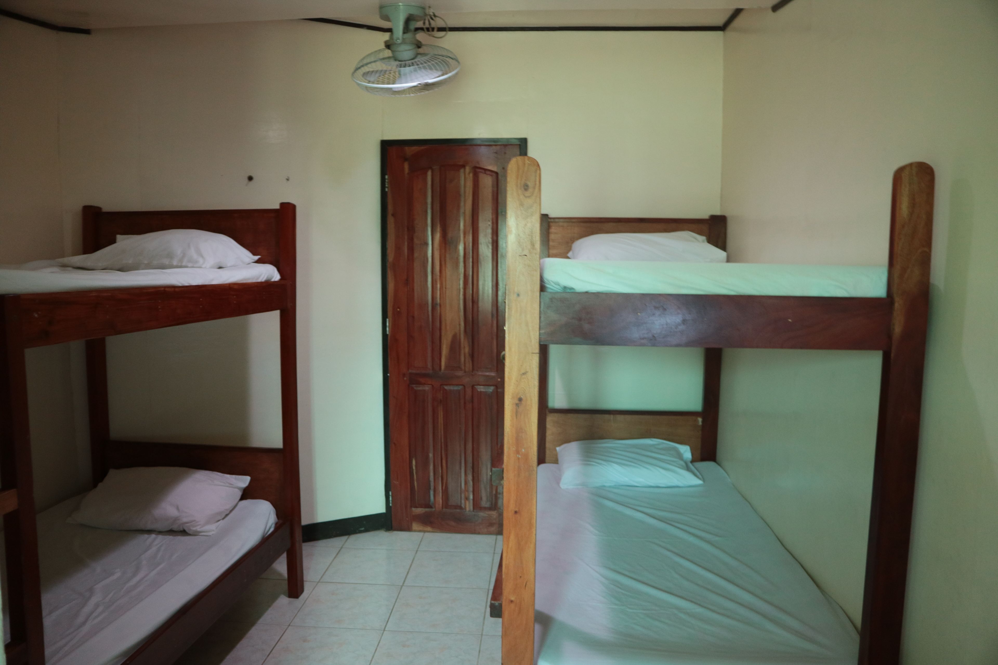 Ein Zimmer mit zwei Etagenbetten, einer Holztür und einem Deckenventilator.