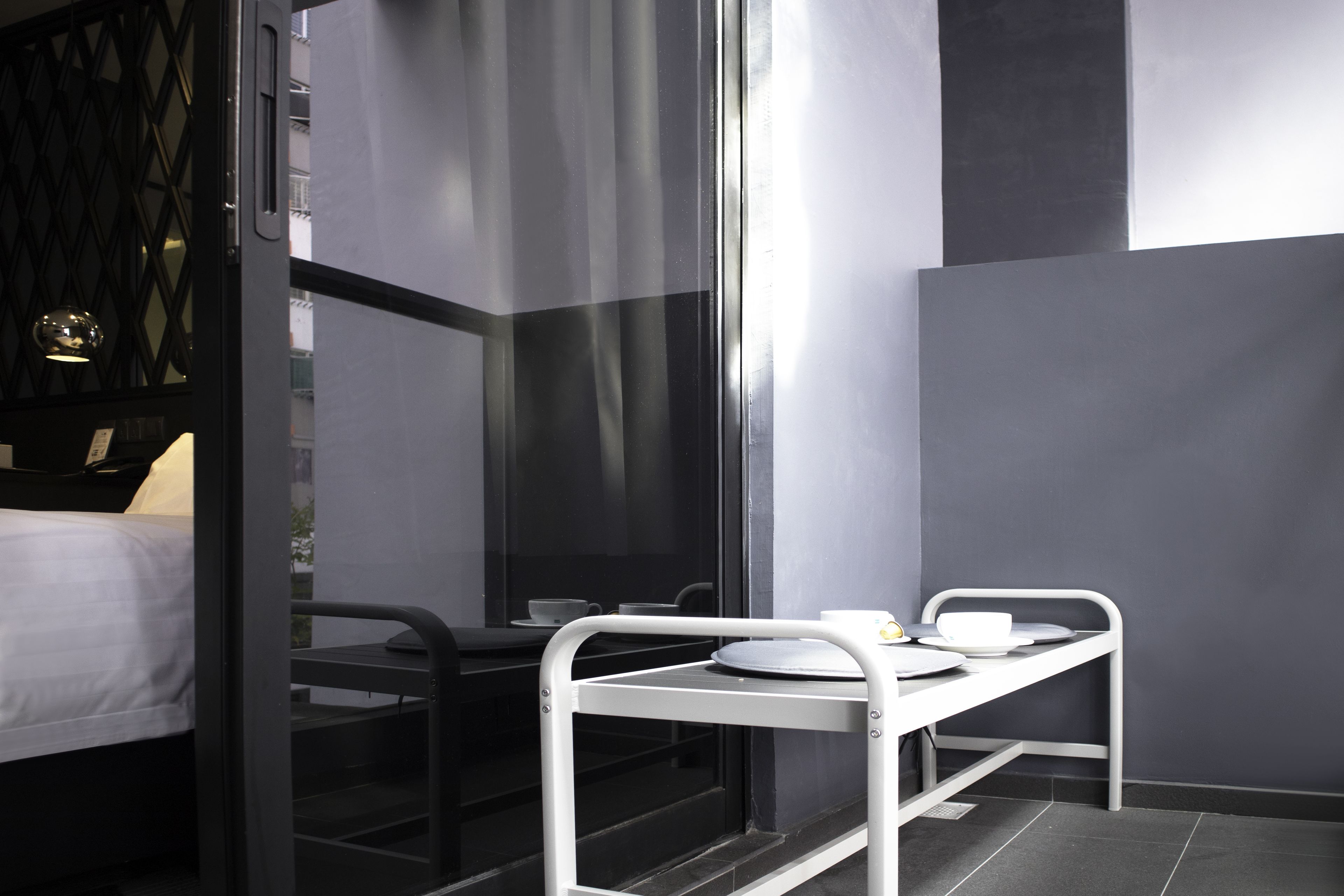 A modern hotel room with a bed, a desk, and a small table with a cup and saucer.