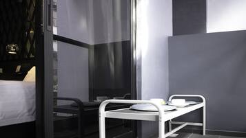 A modern hotel room with a bed, a desk, and a small table with a cup and saucer.