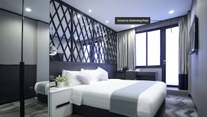 Een moderne hotelkamer met een groot bed, een bureau en uitzicht op het zwembad.
