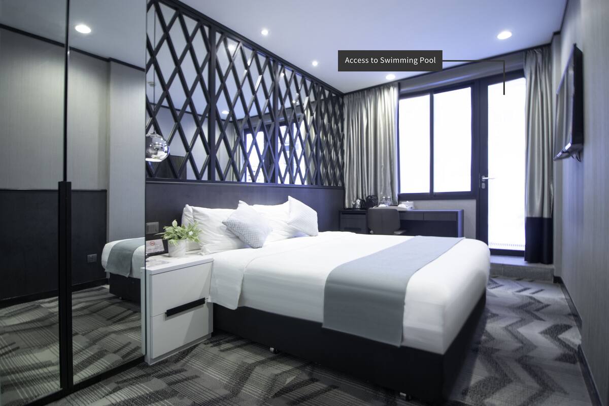 Une chambre d’hôtel moderne avec un grand lit, un bureau et une vue sur la piscine.