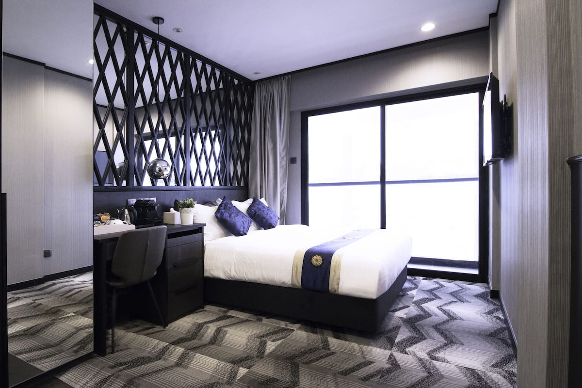 Une chambre d’hôtel moderne, équipée d’un lit, d’un bureau et d’une chaise.