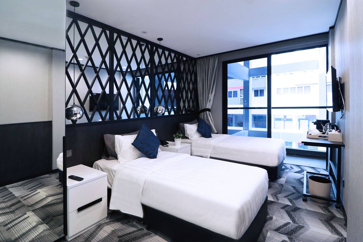 Une chambre d’hôtel avec deux lits, un bureau, une télévision et une fenêtre donnant sur la ville.
