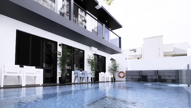 Een modern gebouw met een zwembad, terras en plantenpotten.