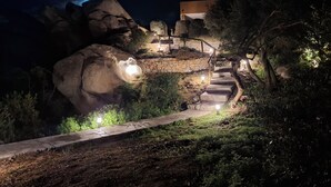 Una escalera de piedra que conduce a un edificio con un muro de piedra y una gran formación rocosa.