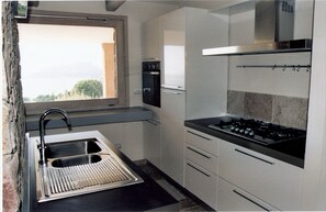Compact kitchen with sink, stove, microwave, and small oven, featuring sleek cabinetry.