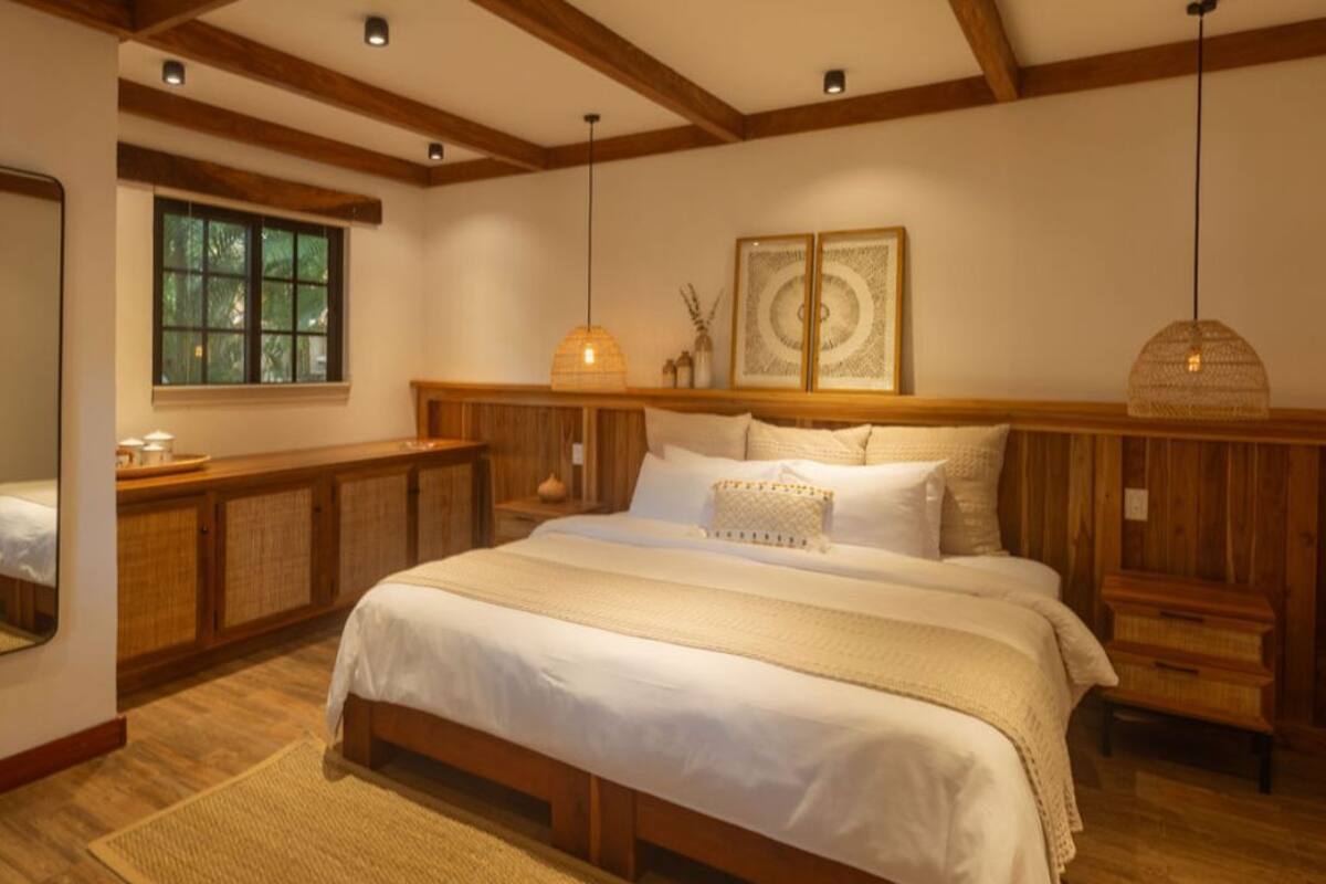 Un dormitorio con una cama grande, cabecera de madera y ventana con vistas a la vegetación.