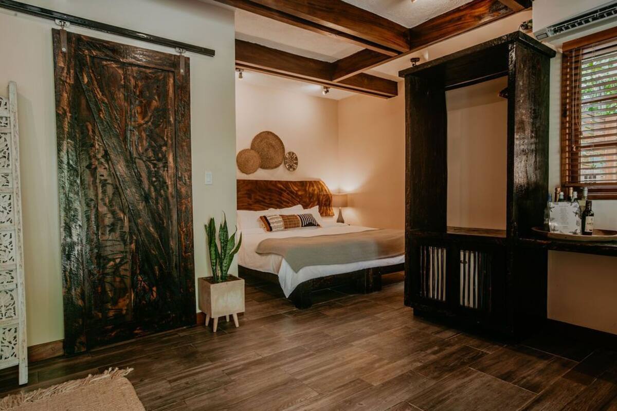 Un dormitorio con cama, mesita de noche y un espejo grande.