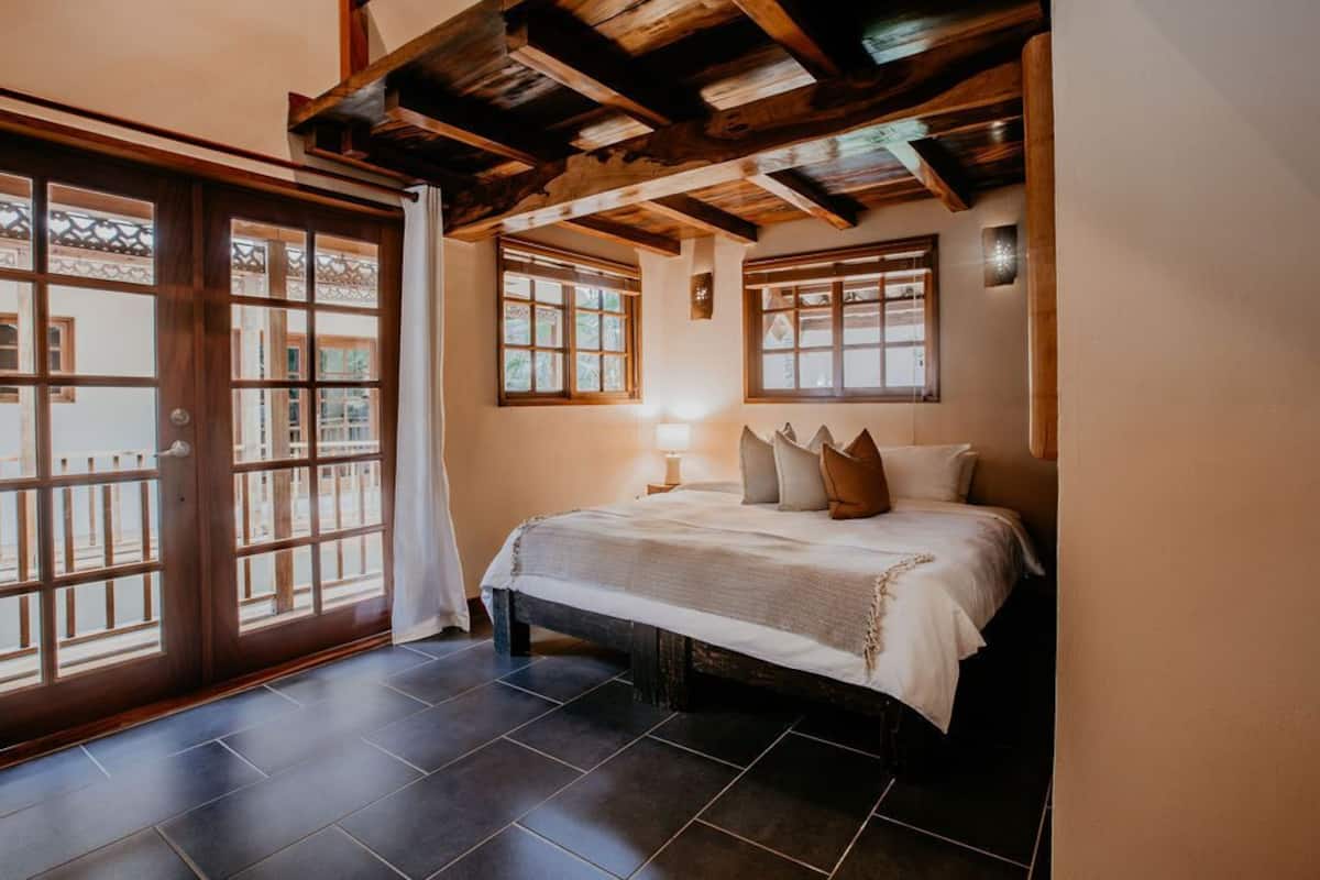 Un dormitorio con una cama, una mesita de noche, una ventana y una puerta.