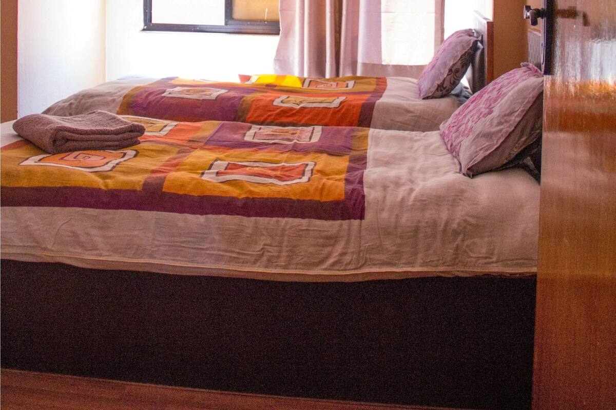 A bedroom with a bed, curtains, a window, and a door.