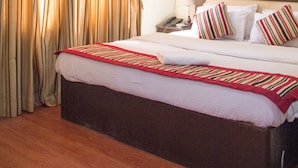 A hotel room with a large bed, a bedside table with a lamp, and a window with curtains. - Sankata Hotel & Apartment (Kathmandu)