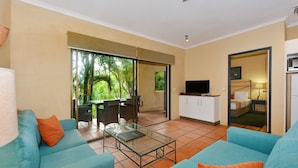 A living room with a glass coffee table, two blue sofas, and a television.