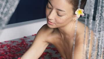 Relax in a serene bathtub surrounded by rose petals.