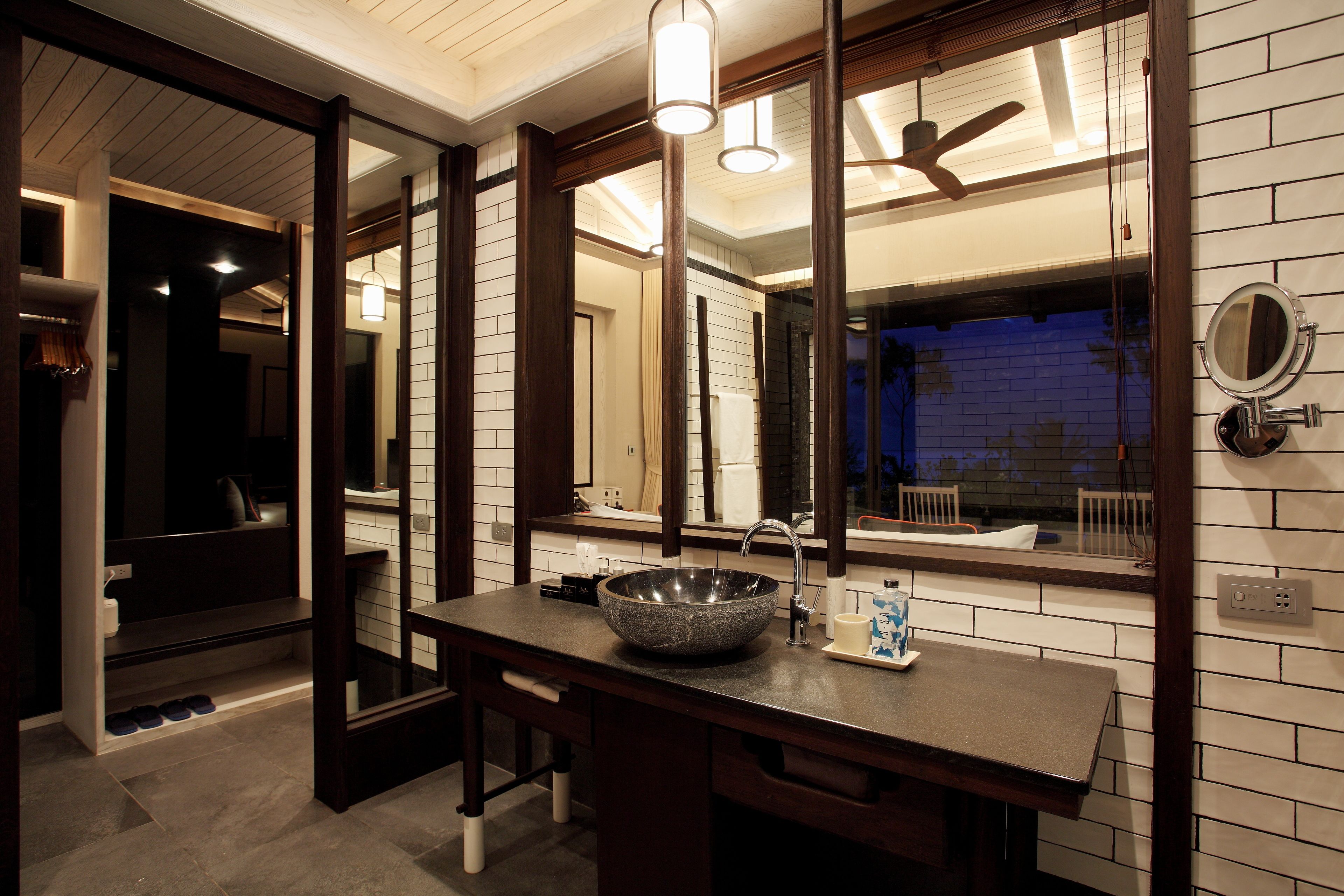 A modern bathroom with a large mirror, a vessel sink, and a ceiling fan.