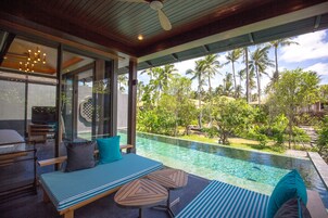 Un espacio lounge moderno al aire libre con piscina, asientos y vistas a palmeras.
