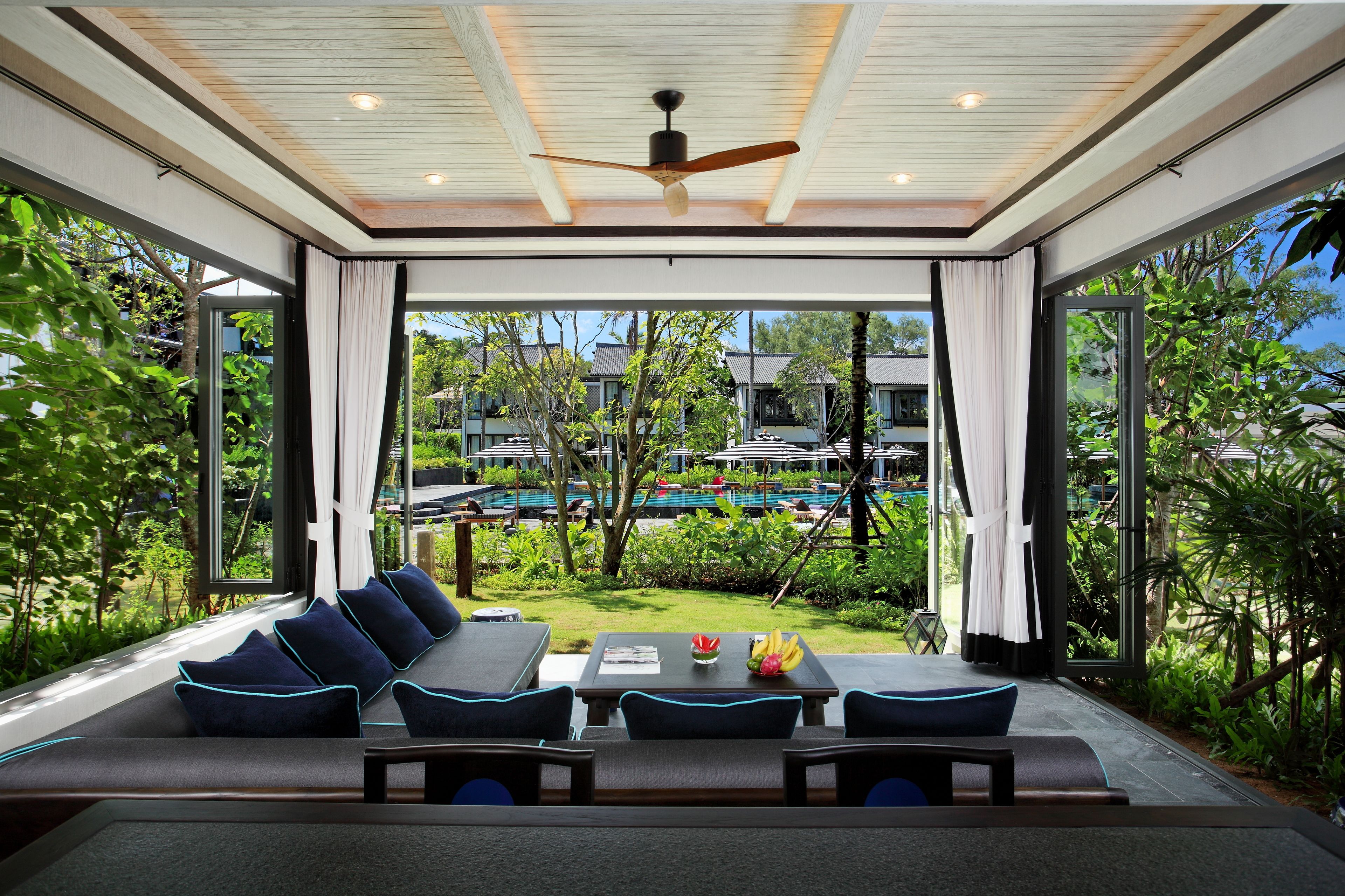 Un espacio moderno para sentarse al aire libre con vistas a una piscina y exuberante vegetación.