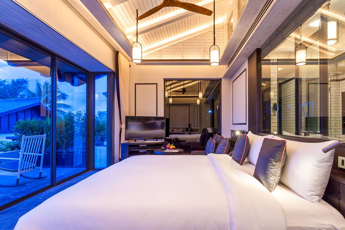 A modern hotel room with a large bed, a television, and a view of the outdoors.