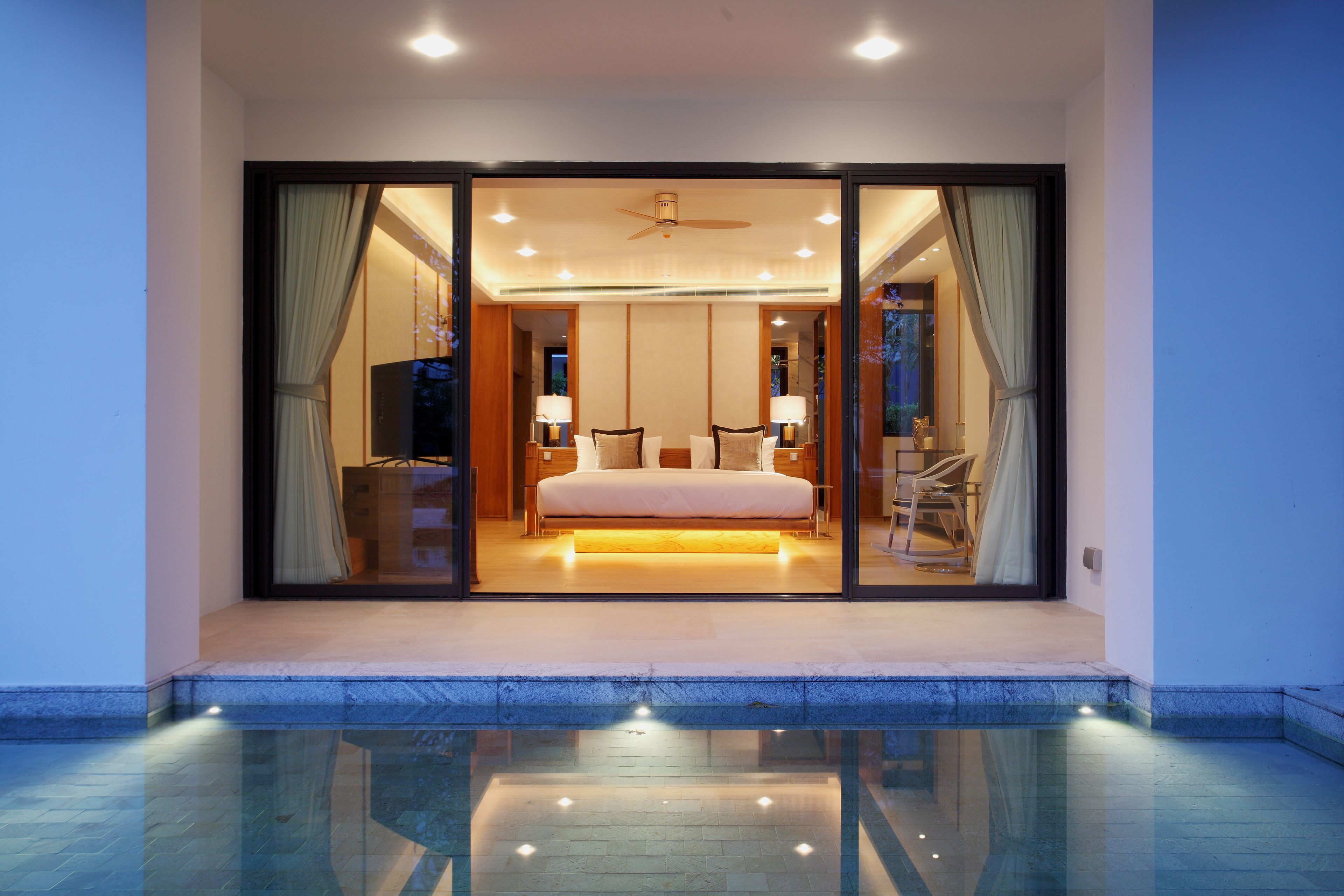 A modern bedroom with a large bed, sliding glass doors, and a ceiling fan.