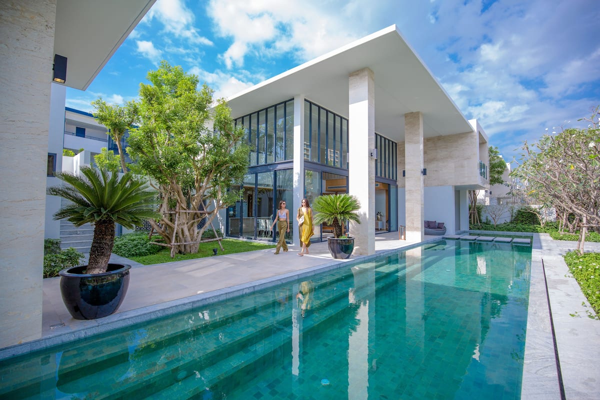 Un bâtiment moderne doté d’une piscine, de grandes fenêtres et d’espaces extérieurs aménagés pour se détendre.