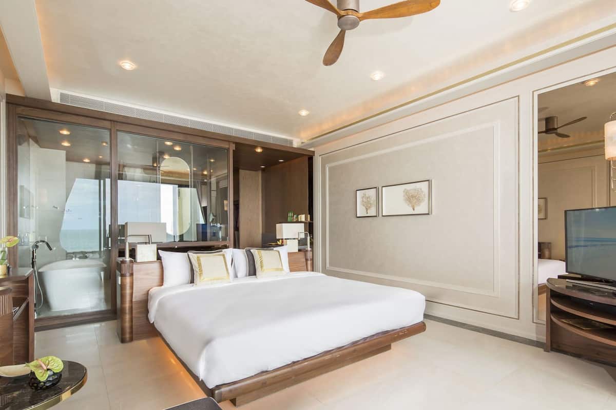 Une chambre d’hôtel avec un grand lit, une télévision, un bureau et une vue sur la mer.