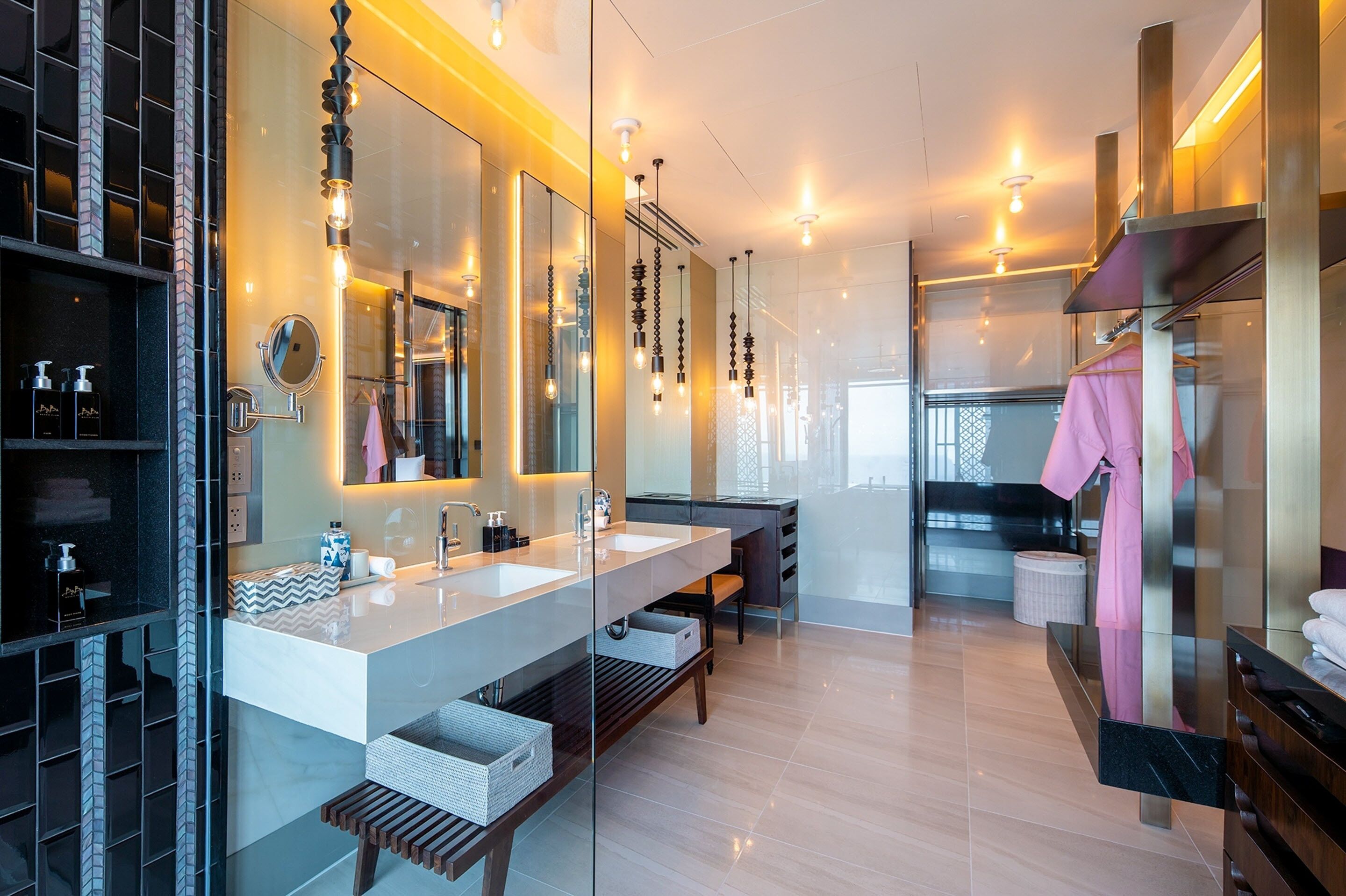 A modern bathroom with a large mirror, two sinks, and a vanity area.